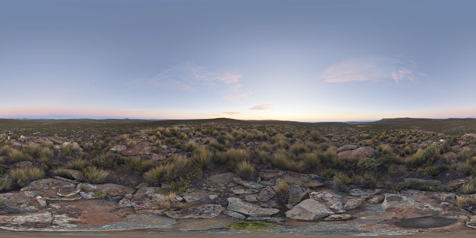 Free, unclipped 24K HDRI of a rocky grassland at dawn: soft pre-sunrise glow, pale blue sky with pink clouds, cool ambient light and gentle warm horizon tint.
