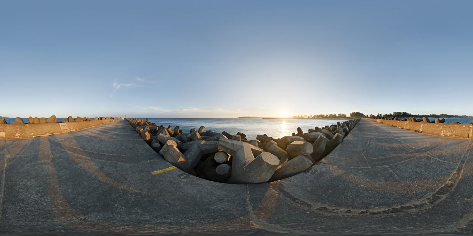 Free 24K unclipped HDRI of a concrete breakwater at sunset: clear sky, warm low sun over calm sea, long hard shadows and high-contrast, crisp coastal light.