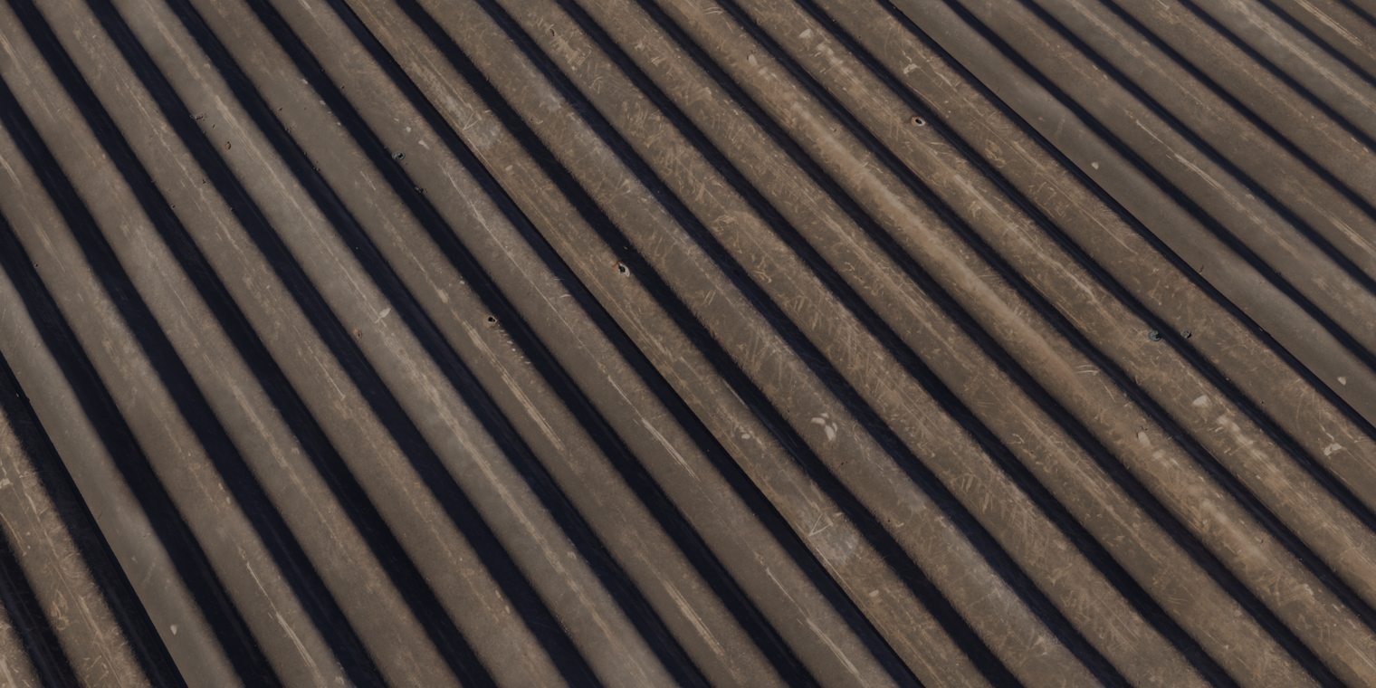 Free 16K texture of corrugated asbestos sheet with dark, dusty, fibrous surface, weathered with scratches, bolt holes and an aged finish.