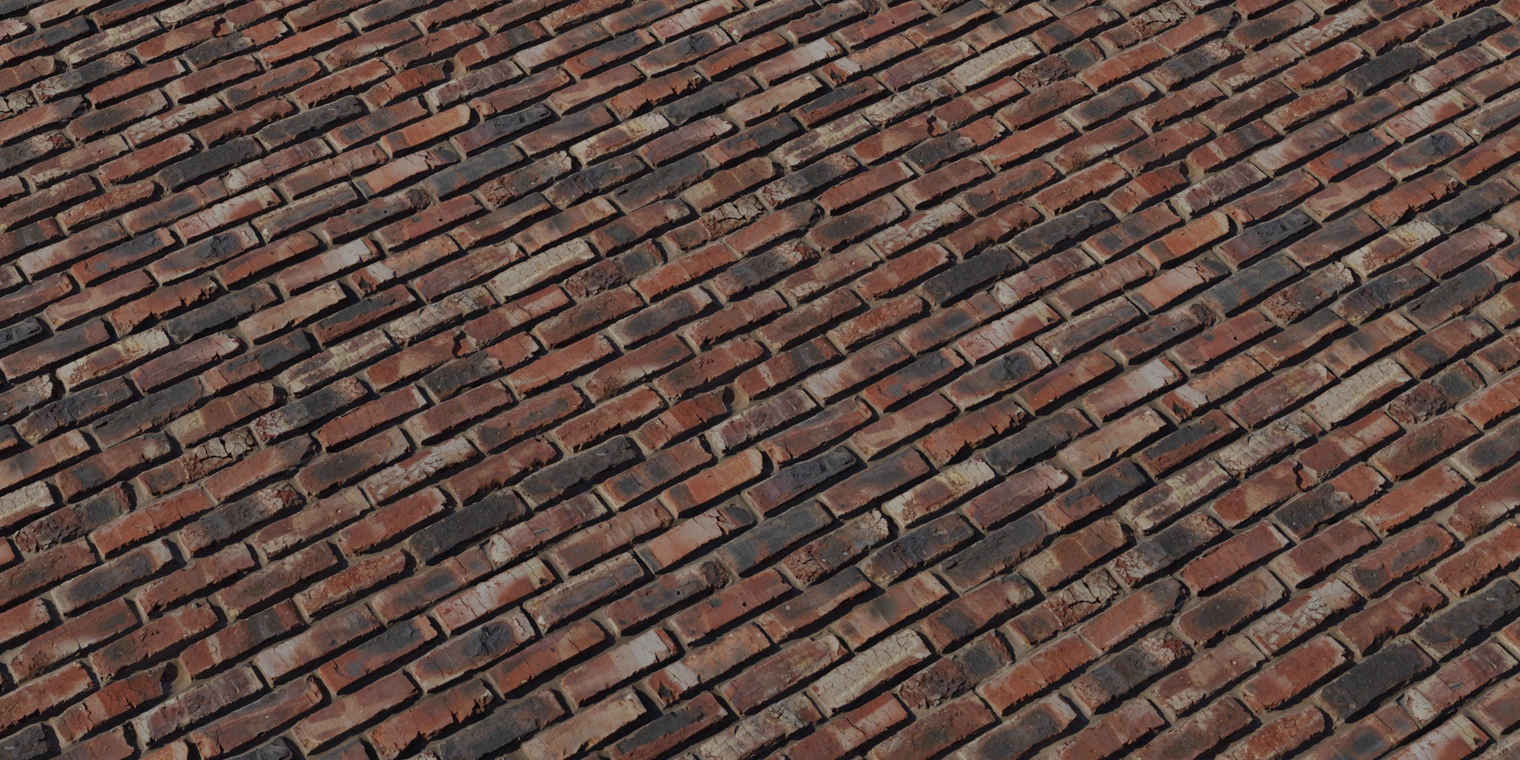 Free 8K texture of a red, rough industrial brick wall with baked-in grime, chipped edges, varied mortar tones and pronounced surface relief.