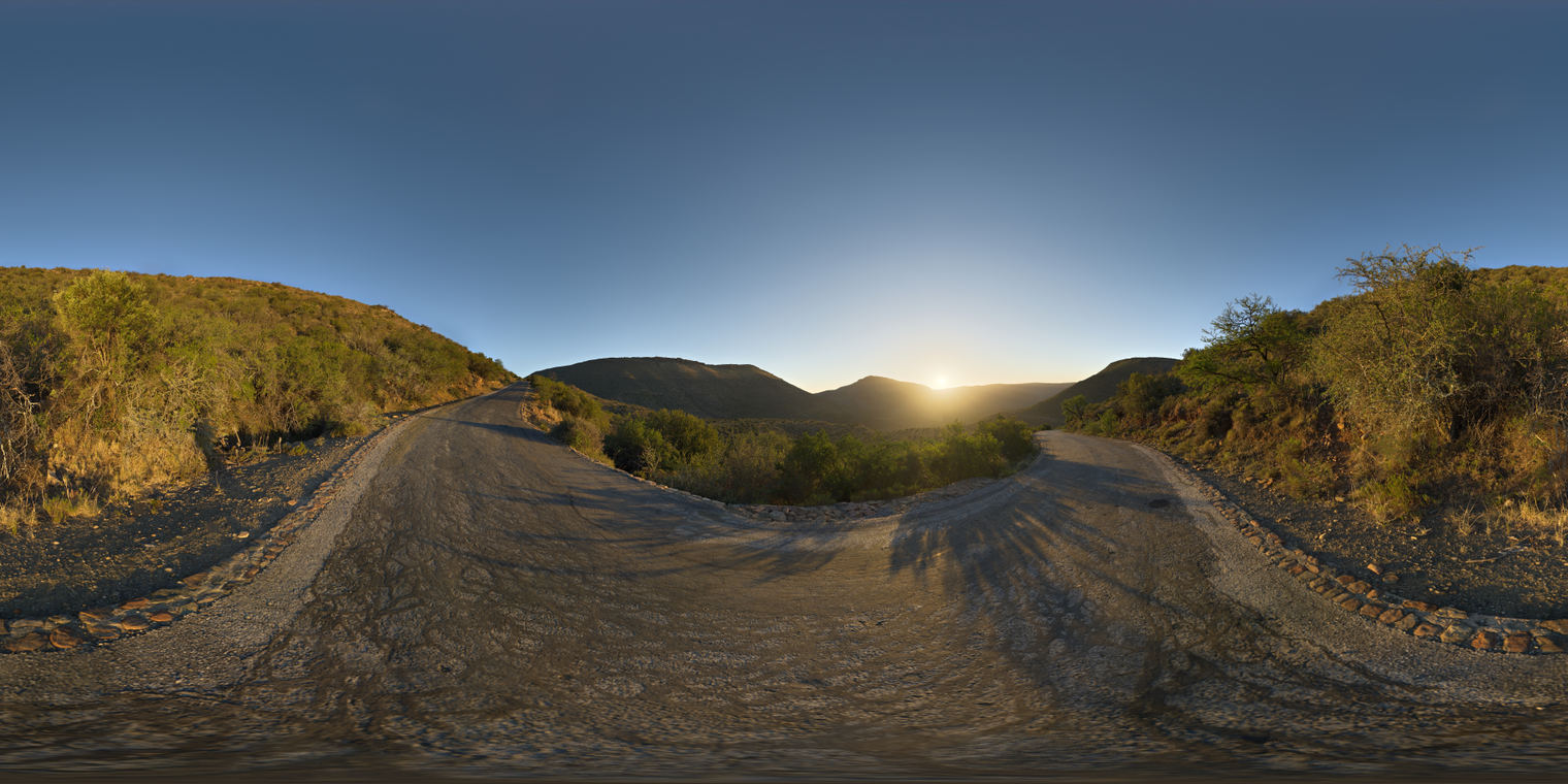 Unclipped, free 24K HDRI of a winding mountain road at sunset: clear sky, warm golden light, sharp sun, long shadows, crisp contrast and cool blue ambient.