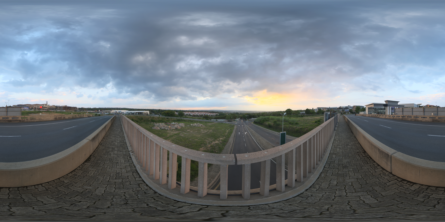 Free 24k unclipped HDRI of a bridge at dusk with soft, low-contrast lighting, partly cloudy skies and a warm sunset glow on the horizon.