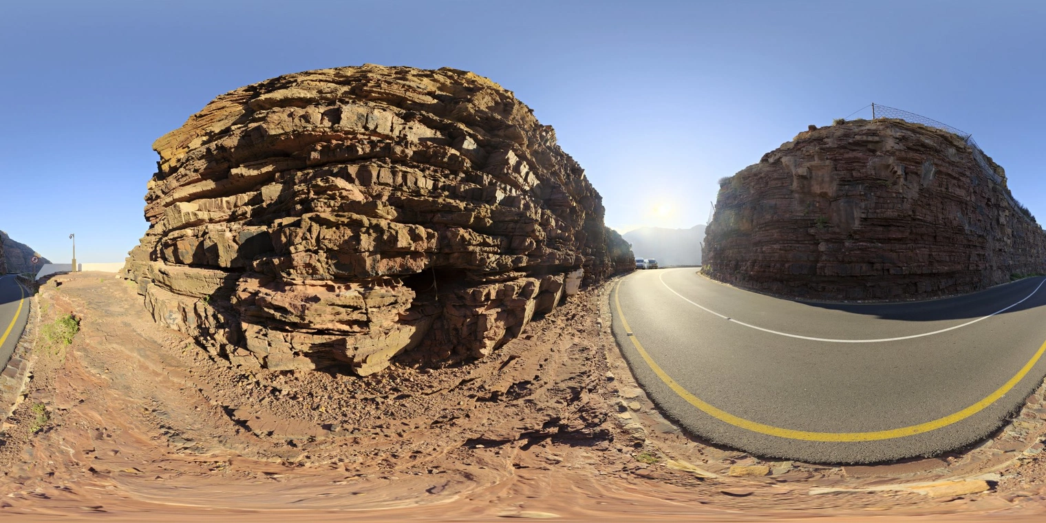 Free 16K unclipped HDRI of a sunlit cliffside road, clear sky and warm late-morning/afternoon sun; high-contrast natural light with strong directional shadows.