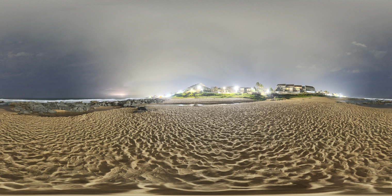 Unclipped, free 24k beach at night with cloudy sky, distant surf, and bright coastal buildings. Cool ambient glow, warm sand, crisp highlights, hard shadows.