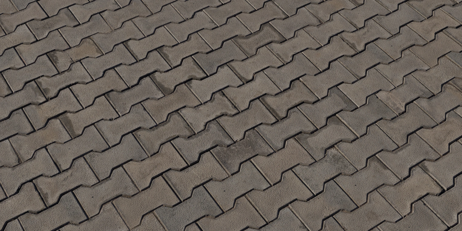 Free 16K texture of interlocking concrete pavers with worn, slightly rough surface, recessed joints and subtle dirt staining on patterned pavement.