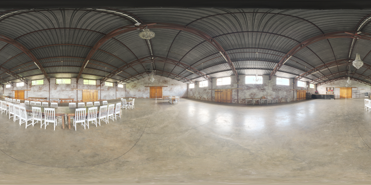 Free unclipped 20k HDRI of an events hall interior with soft natural light through windows, high metal roof, worn brick walls and concrete floor.
