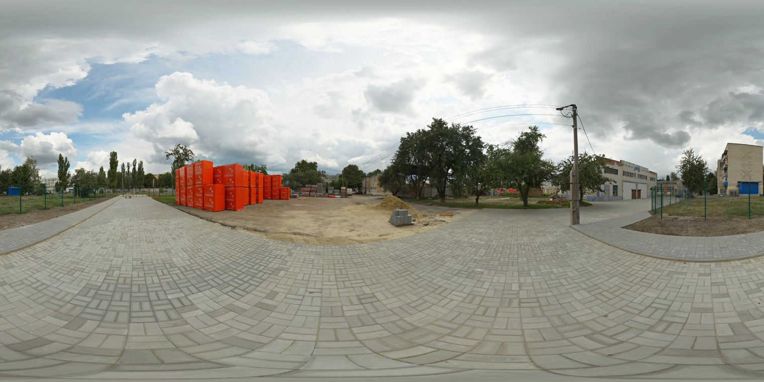 Free 16K unclipped HDRI of a factory yard with partly cloudy morning/afternoon skies, soft natural, low-contrast light, brick paving and orange stacks.