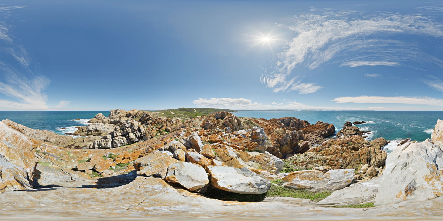 Free 24K unclipped HDRI: bright seaside midday on rocky cliffs, hard sun and crisp shadows, deep blue sky and ocean, warm stone hues, wispy cirrus.