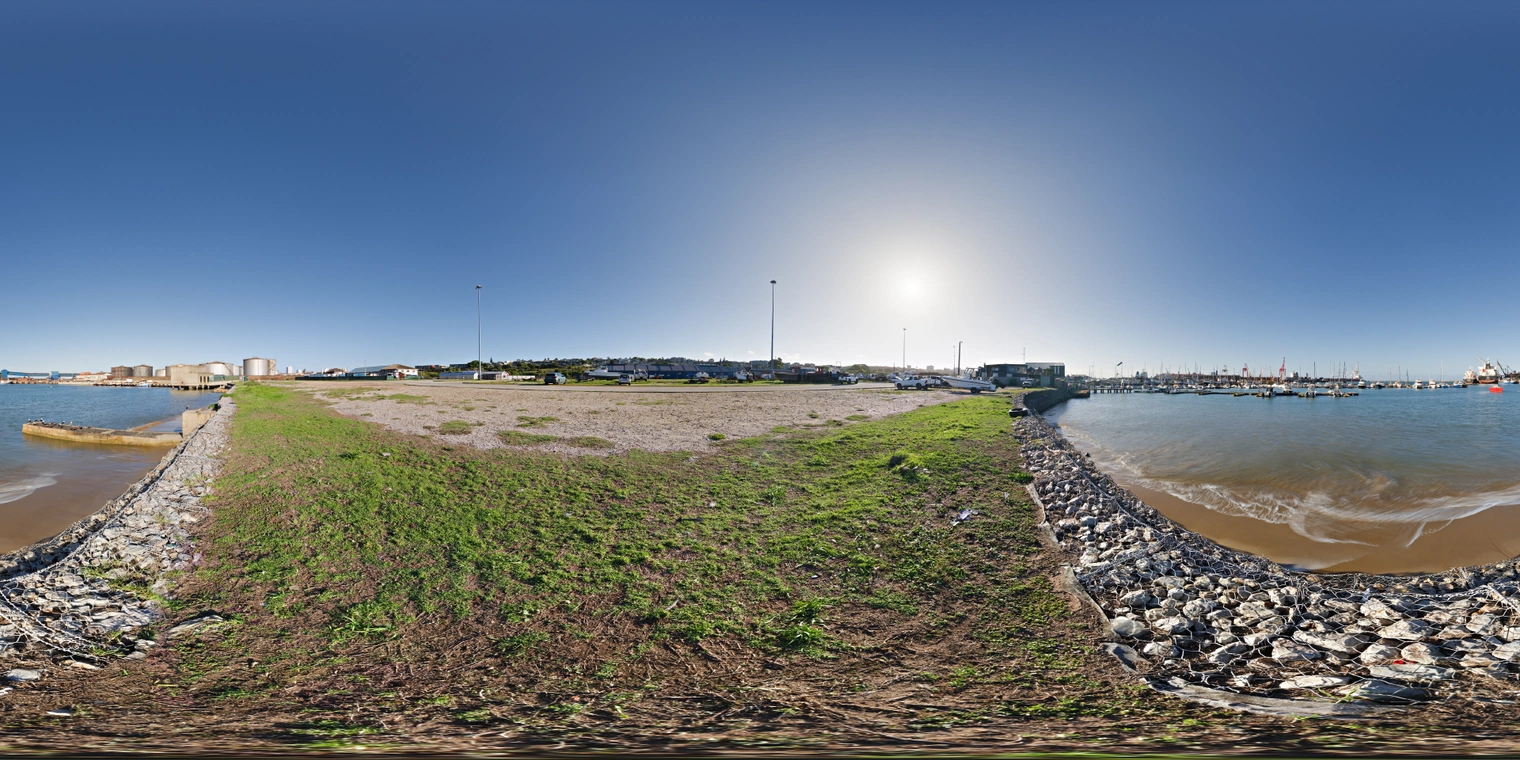 Unclipped, free 24K HDRI of Gqeberha (Port Elizabeth) harbor under clear blue sky, bright low sun, hard coastal contrast, rocky shore and calm water, distant boats and cranes.