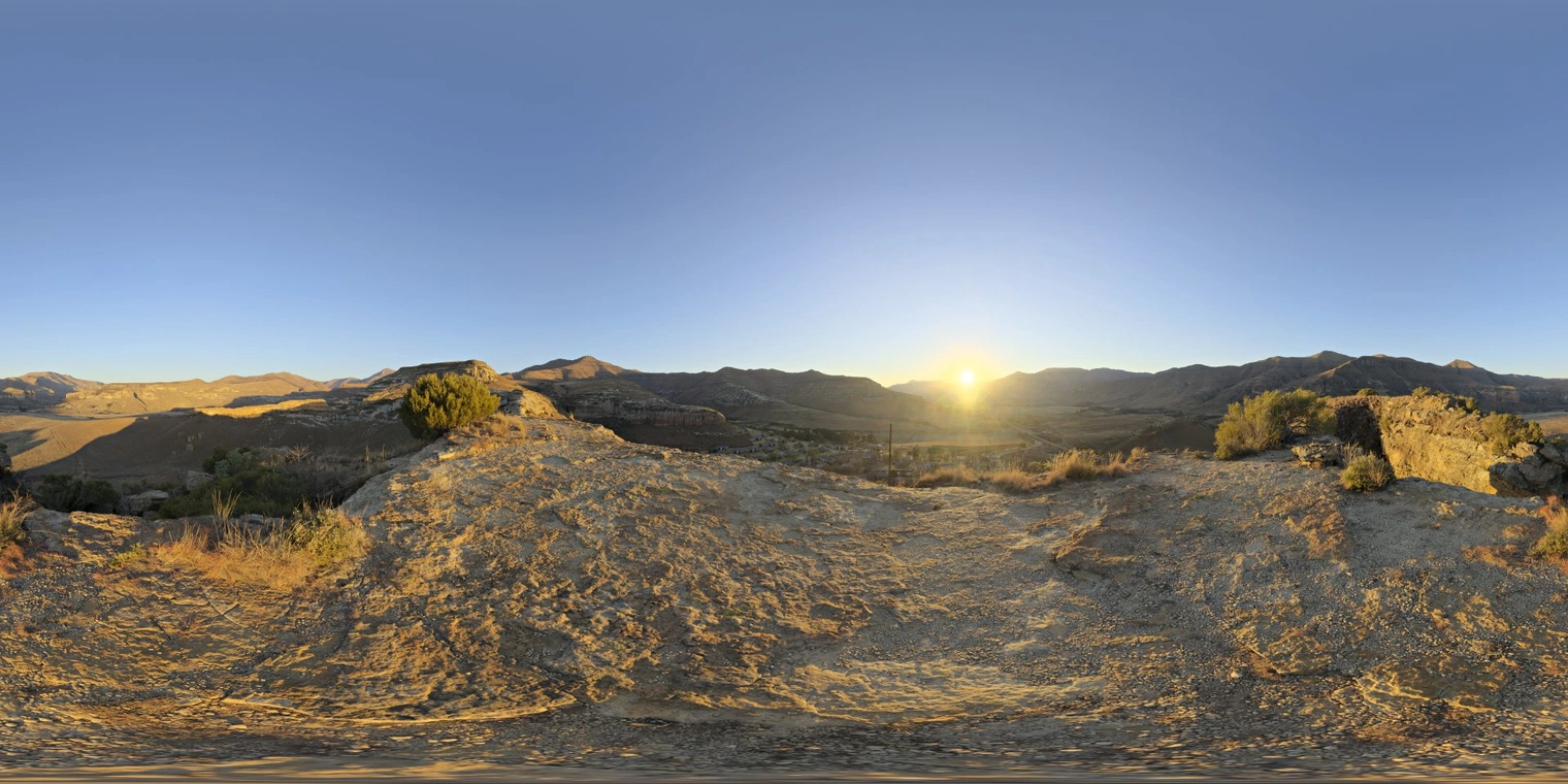 Free 16K, unclipped HDRI showing a clear, high-contrast golden sunset over rocky ridges and a valley, warm low sun casting long shadows and crisp natural light.