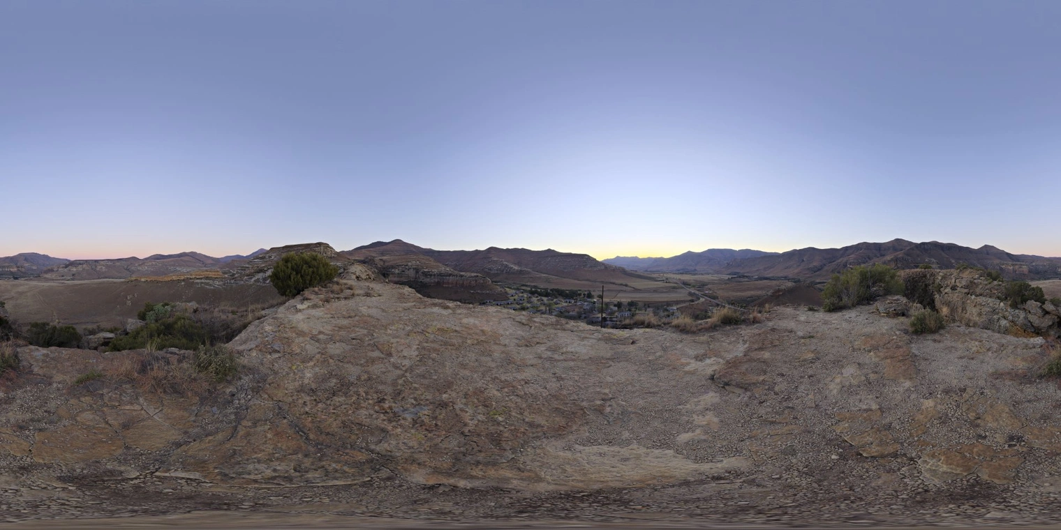 Unclipped, free 16K HDRI of a clear dusk valley: low-contrast cool-blue sky, warm horizon glow, soft natural light on rocky foreground and distant mountains.