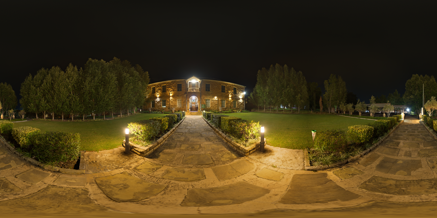 Unclipped, free 24K HDRI of an old house at night: warm tungsten lamps, stone paths and lawns, deep shadows under a clear dark sky, with hard golden light from below.