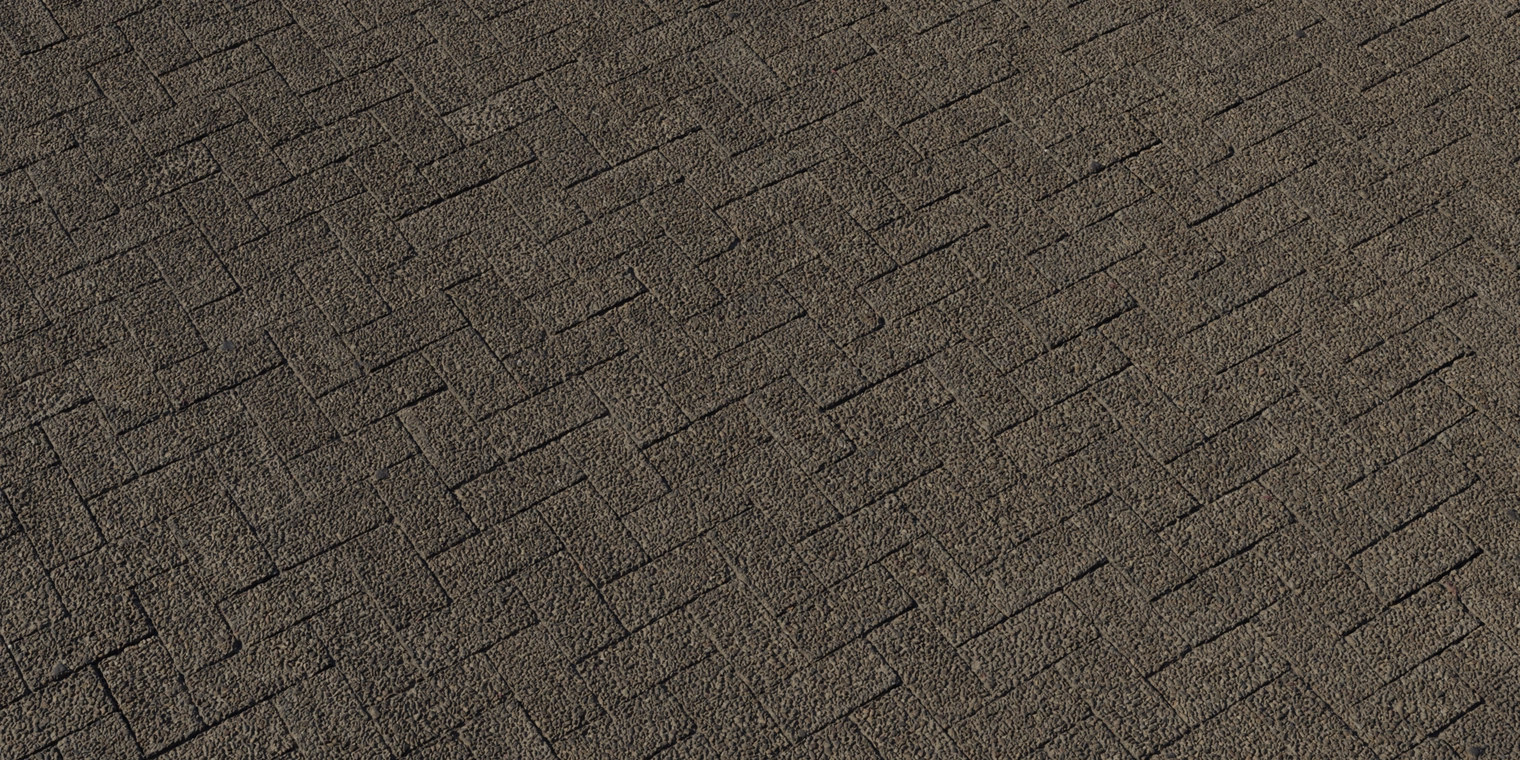 Free 8k texture of herringbone interlocking bricks with a coarse, pebble-embedded, weathered surface, rough uneven grain and recessed grout lines.