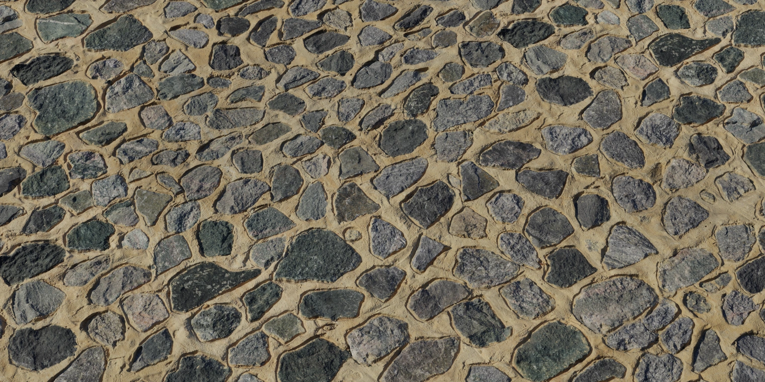 Free 8K texture of coarse stonework: irregular dark gray rocks embedded in warm tan mortar with rough, uneven surfaces, visible seams and color variation.