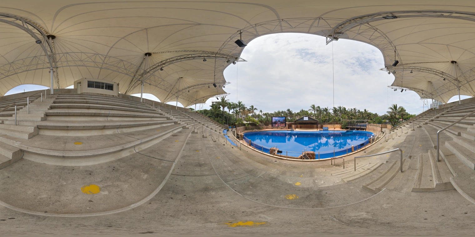 Unclipped, free 24K HDRI of an open air dolphin stadium under bright overcast skies, soft light, blue pool reflections, shaded seating under white canopies.