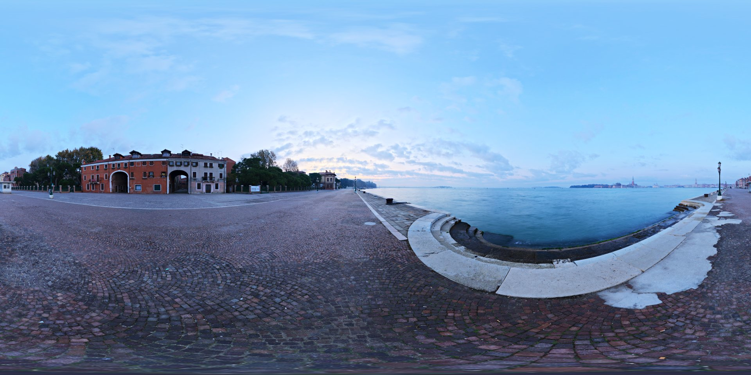 Free 16K unclipped HDRI: soft, low-contrast Venice dawn with cool blue skies, pale warm horizon glow, partly cloudy light, calm sea and waterfront reflections.