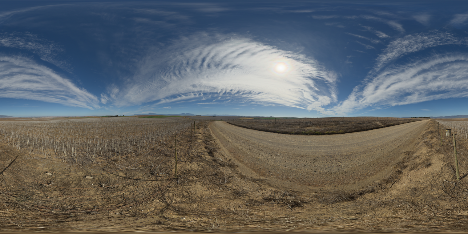 Unclipped, free 24K HDRI of a sunny farm road between dry fields under sweeping cirrus clouds. Bright blue sky, sharp shadows, warm earth tones.