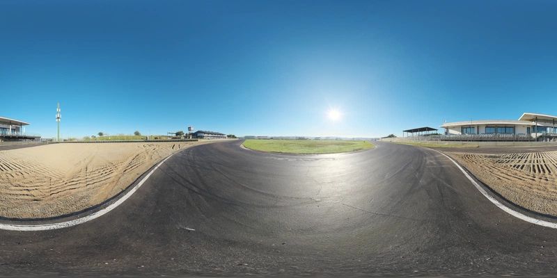 Free 20K unclipped HDRI: clear, high-contrast morning sun over a race track curve, low-angle warm light, sharp shadows and bright specular highlights on asphalt and sand.